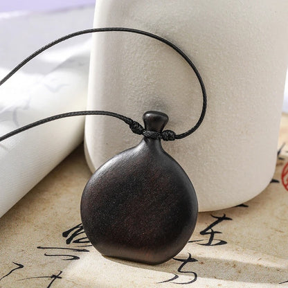 Collier long mixte en bois naturel de santal noir avec pendentif élégant de style bohème et chic.