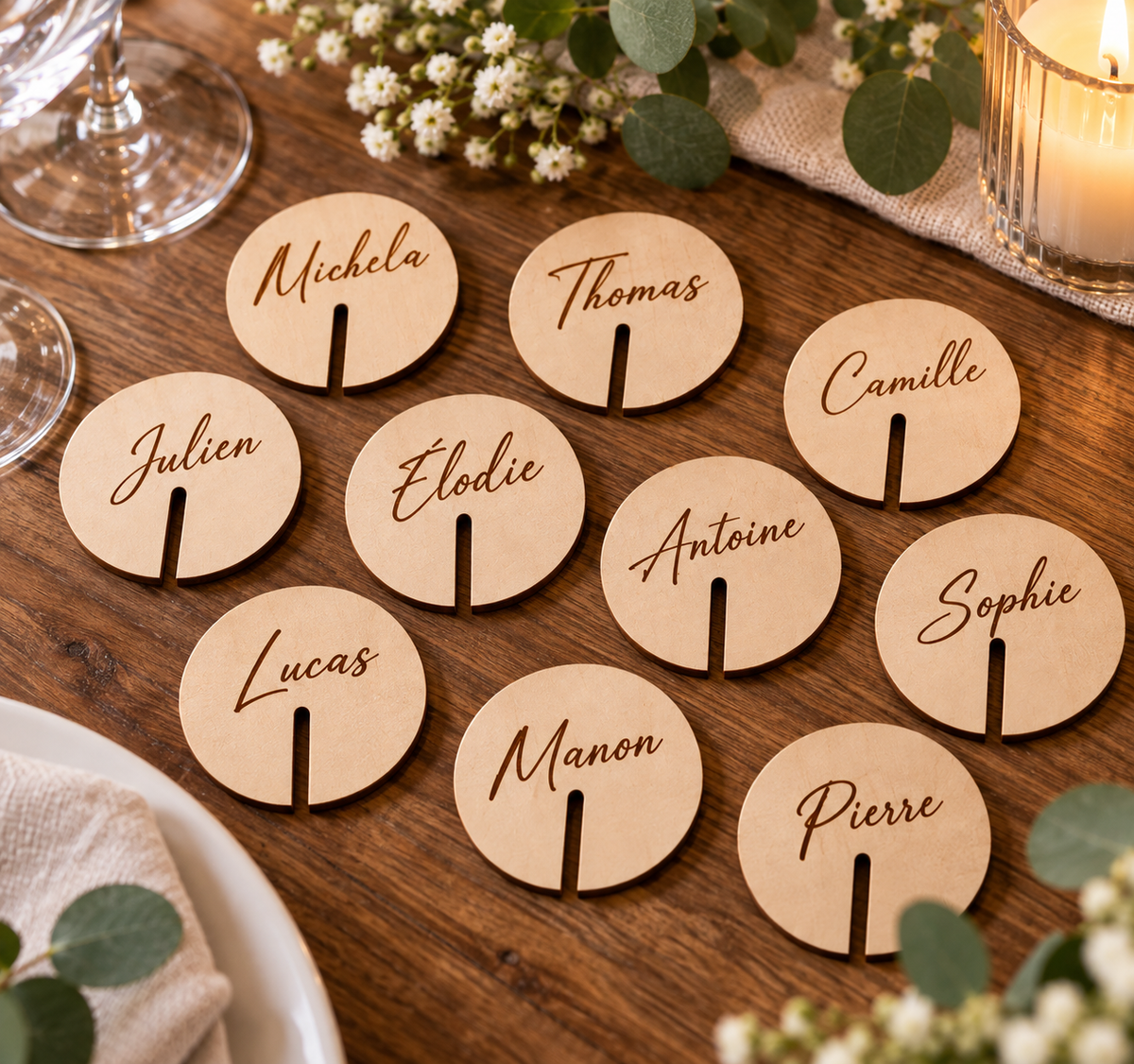 Marque-verres ronds en bois personnalisés avec prénoms disposés sur une table